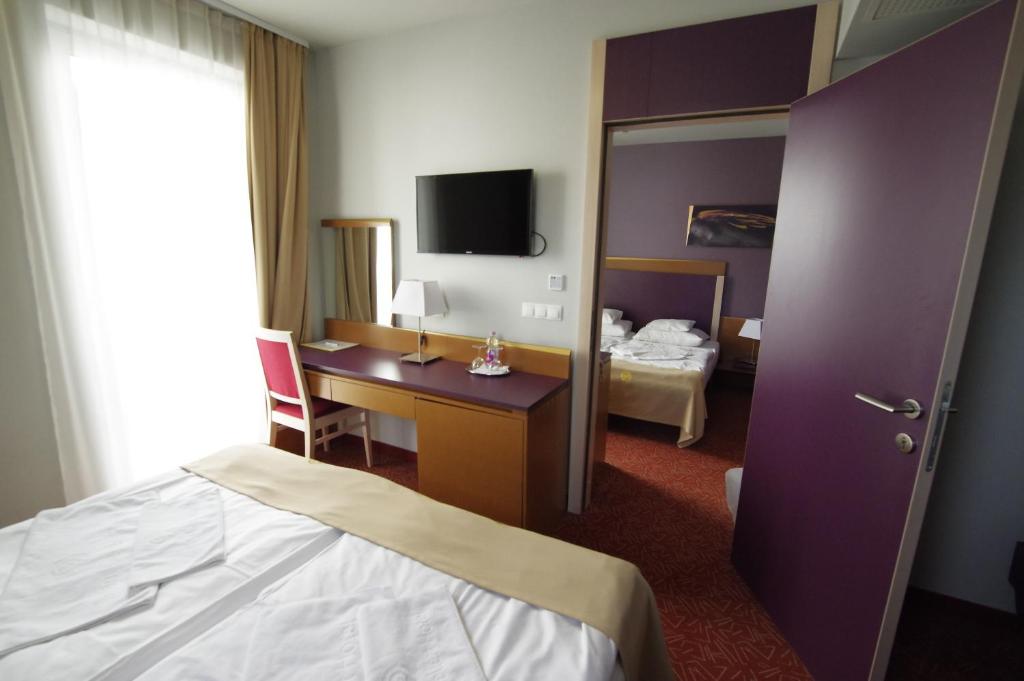 a hotel room with a bedroom with a bed and a desk at Szent Gellért Hotel in Székesfehérvár