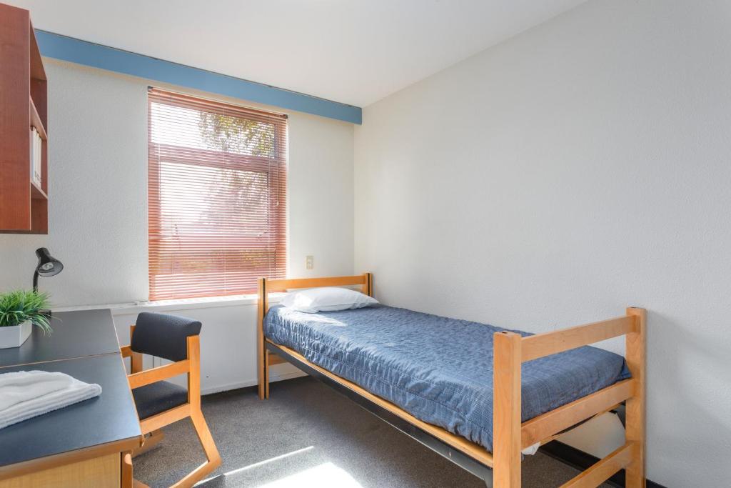 a bedroom with a bed and a desk and a window at Pacific Spirit Hostel in Vancouver