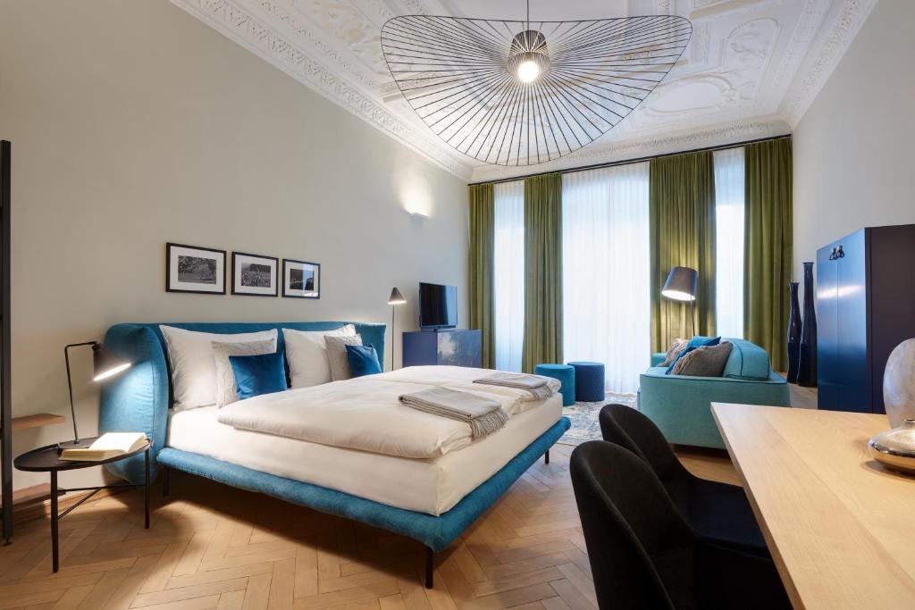 a large bedroom with a blue bed and a table at Arcade Apartments in Bolzano