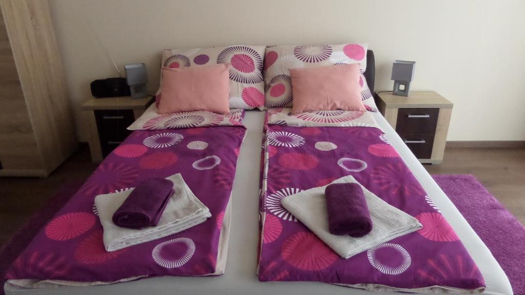ハイドゥソボスローにあるRex Apartmanのピンクと紫のシーツと枕が備わるベッド1台