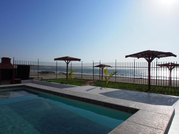 una piscina con sombrillas junto al océano en Los Maderos de Colan: Casa #5 +BBQ+Pool+WiFi, en Colán