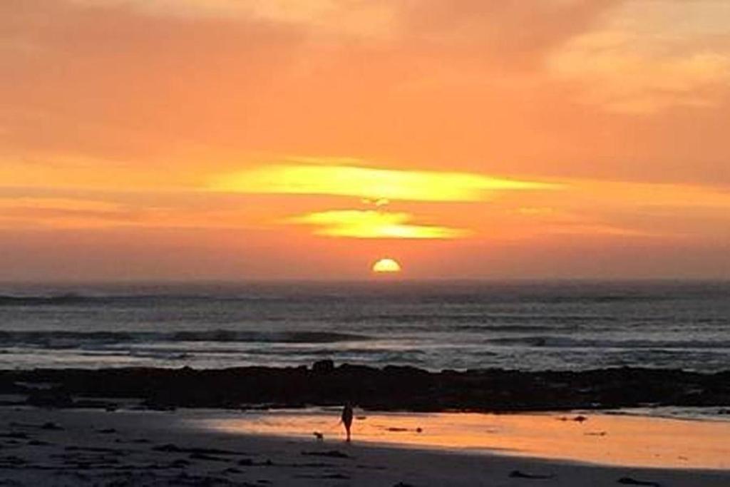 a person standing on the beach at sunset at Wavey Beach Room in Melkbosstrand
