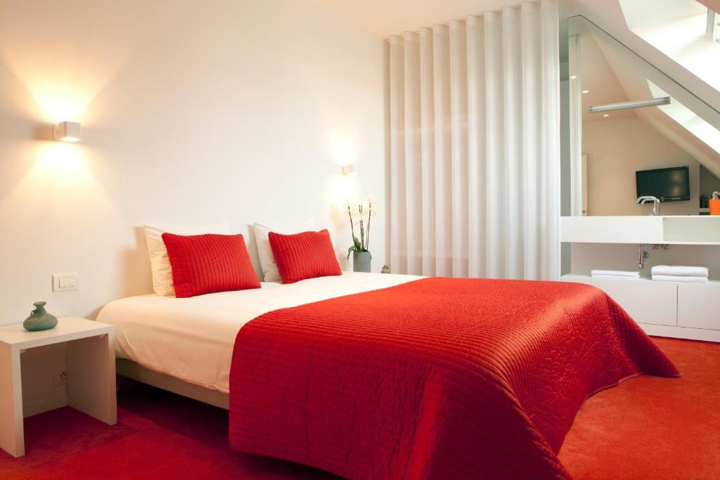 a bedroom with a large bed with red pillows at Guesthouse Polderlicht in Blankenberge