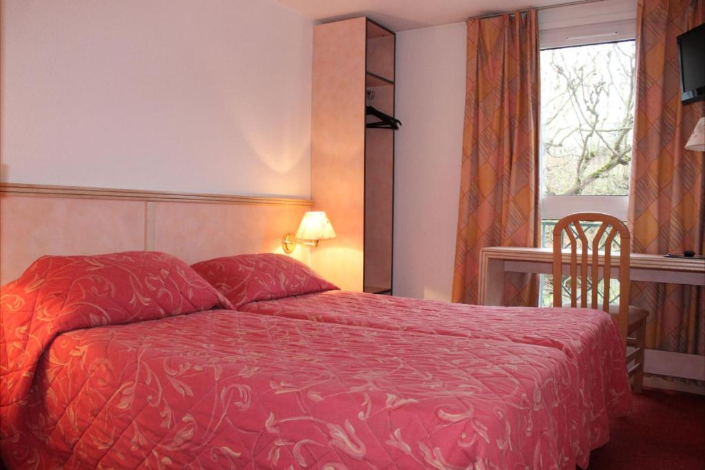 a bedroom with a red bed and a window at Hotel Le Village in Gif-sur-Yvette