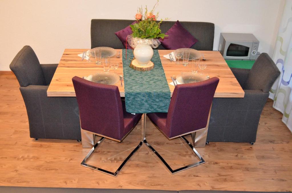 une table à manger avec des chaises violettes et une table avec dans l'établissement Apartment Mia, à Bad Schönborn