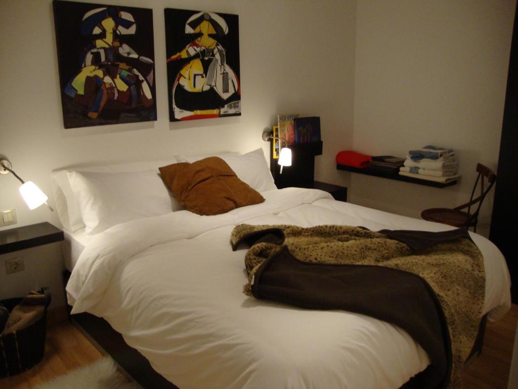 Un dormitorio con una cama blanca con una manta. en Triana Teatro VV, en Las Palmas de Gran Canaria