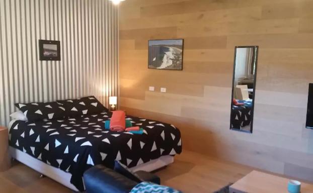 a bedroom with a black and white bed and a mirror at Avoca Beach and Bush in Avoca Beach