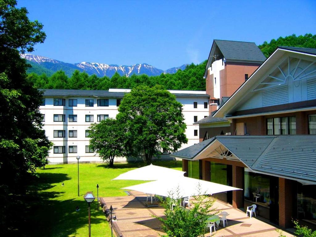 ein Gebäude mit Tischen und Stühlen vor einem Gebäude in der Unterkunft Azumino Hotaka View Hotel in Azumino