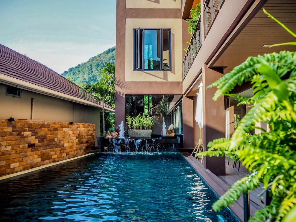 a swimming pool in front of a building with a water fountain at West Key Kamala Apartment in Kamala Beach