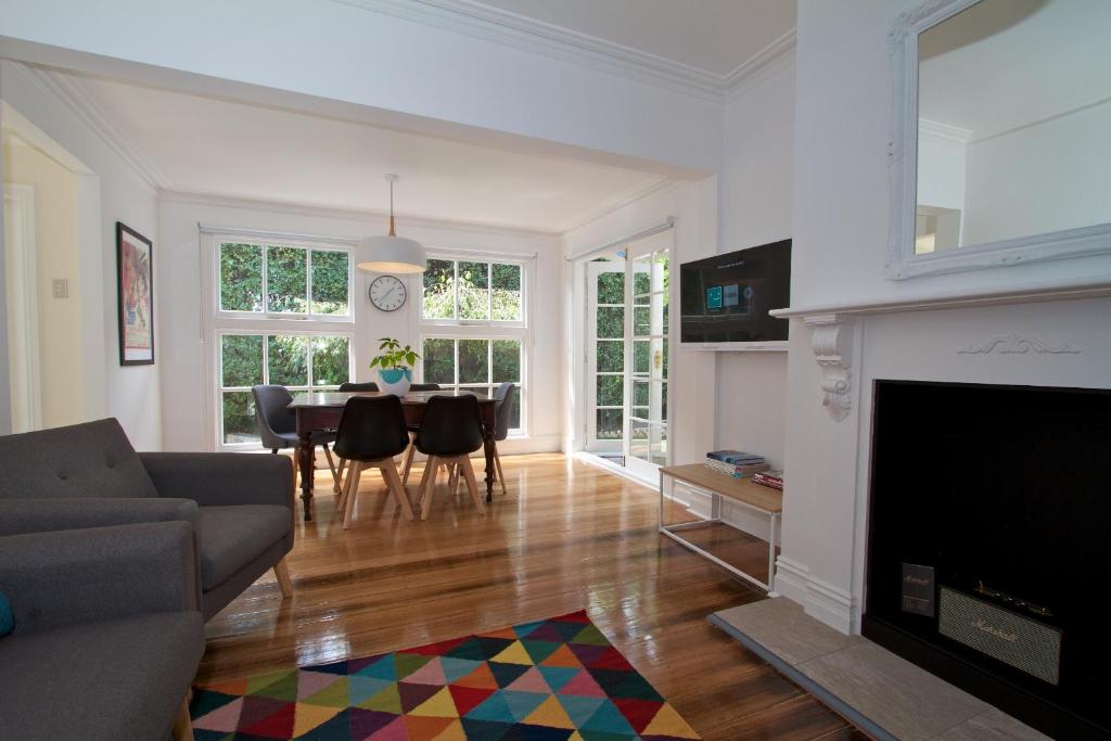 a living room with a fireplace and a table with chairs at Strahan House in Hobart