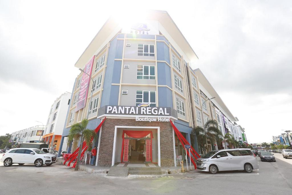 Un grand bâtiment avec des voitures garées dans un parking dans l'établissement Pantai Regal Boutique Hotel, à Kuantan