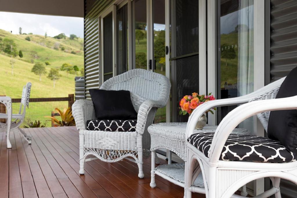 a porch with white wicker chairs and a table at Country Mile Escape in Canungra