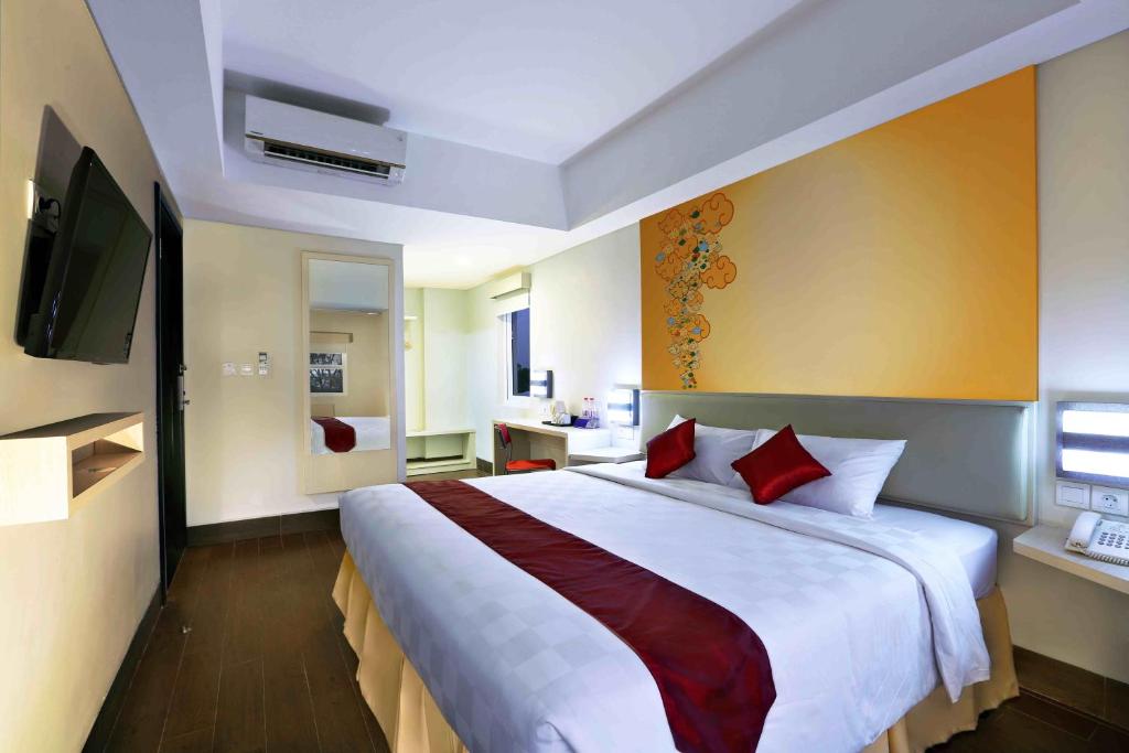 1 dormitorio con 1 cama blanca grande con almohadas rojas en Cordela Hotel Cirebon, en Cirebon