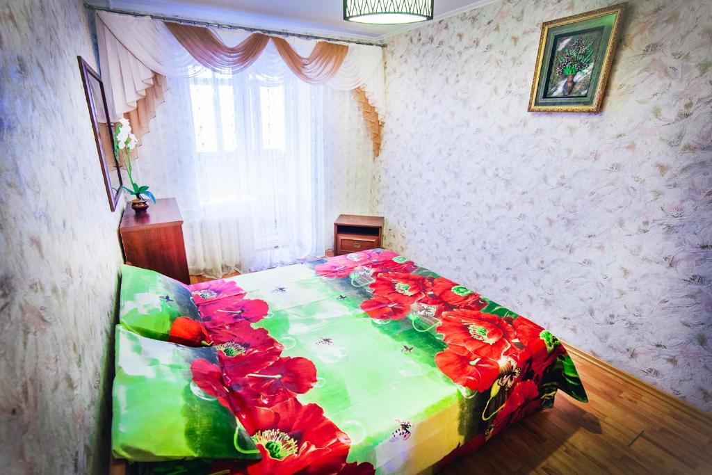 ヴィーンヌィツャにある2-bedroom on Mykolaychuka streetのベッドルーム1室(赤い花のベッド1台付)