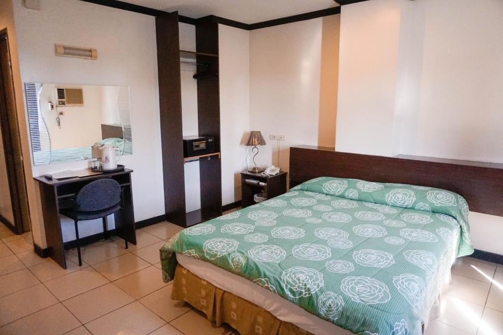 Schlafzimmer mit einem Bett, einem Schreibtisch und einem Waschbecken in der Unterkunft Crowne Garden Hotel in Cebu City
