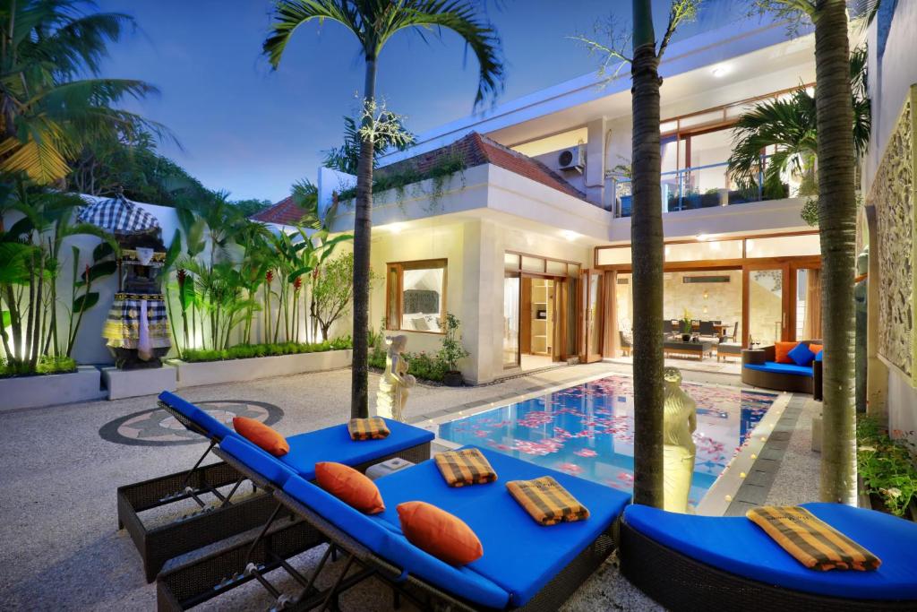 ein Haus mit einem Pool mit zwei blauen Tischen in der Unterkunft Villa Mawar Legian in Legian