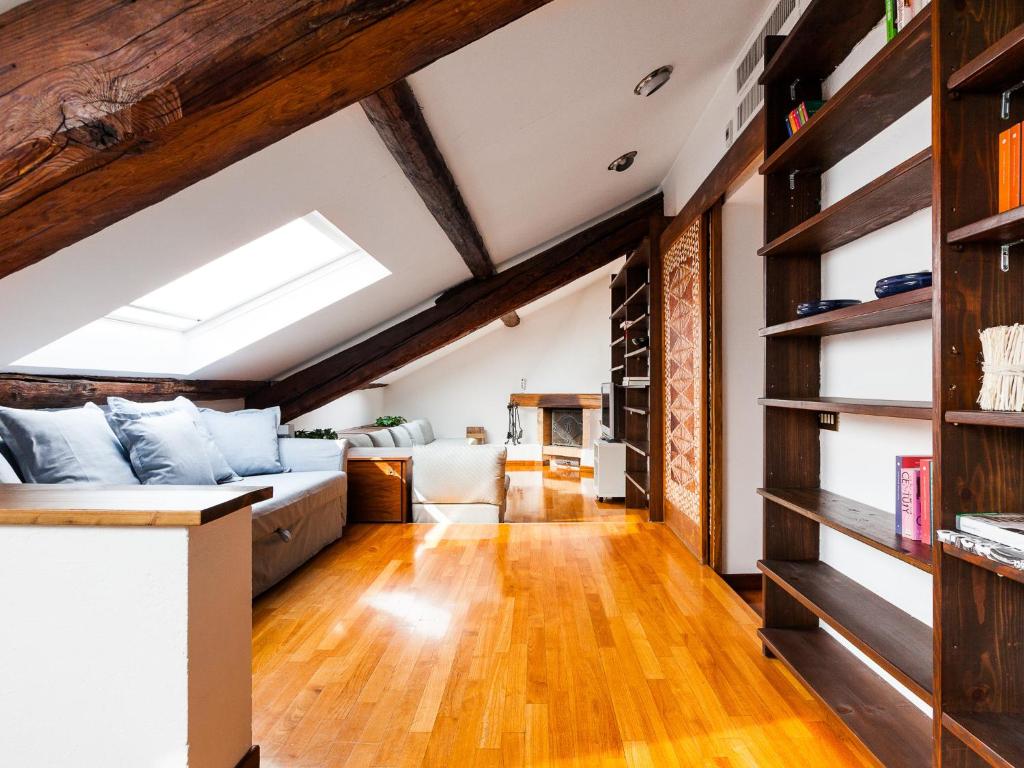 ein Wohnzimmer im Dachgeschoss mit einem Sofa und Holzböden in der Unterkunft easyhomes - Corso Como Maroncelli in Mailand