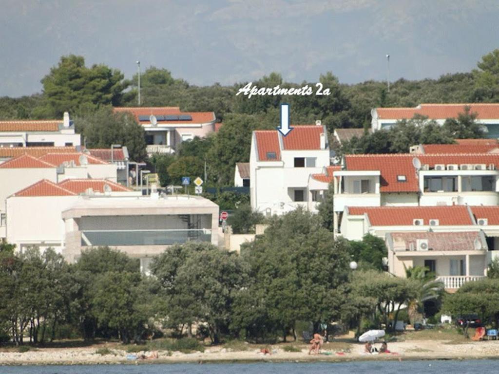 een groep gebouwen op een heuvel naast het water bij Apartments 2A in Petrcane
