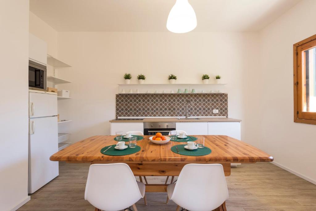 a kitchen with a wooden table and white chairs at BOBO' in Marina di Ragusa