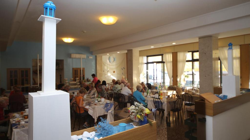 un grupo de personas sentadas en mesas en un restaurante en Hotel Lugano, en Cattolica