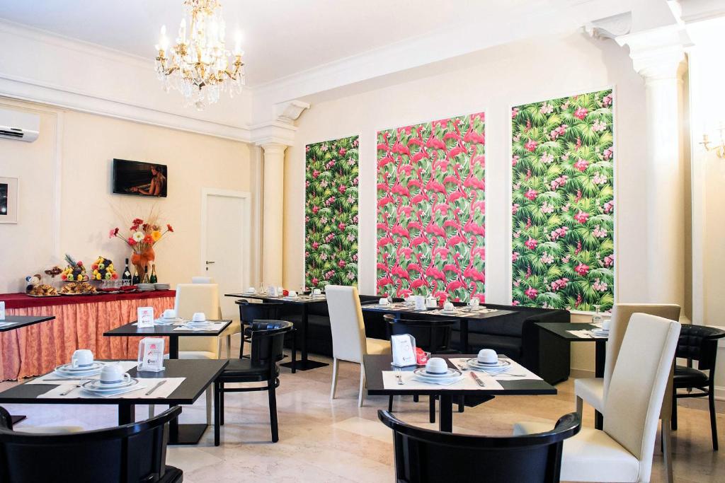 Hotel Palombella & Restaurant في فروزينوني: مطعم بالطاولات والكراسي وجدار زهري كبير