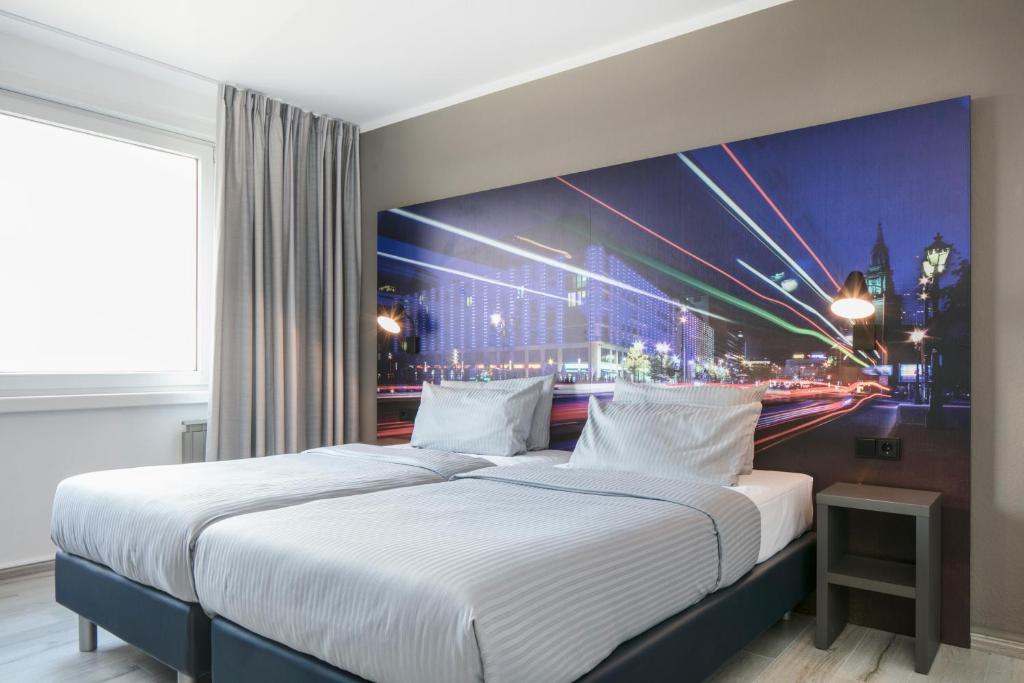 a bedroom with two beds with a painting of a city at Comfort Hotel Lichtenberg in Berlin