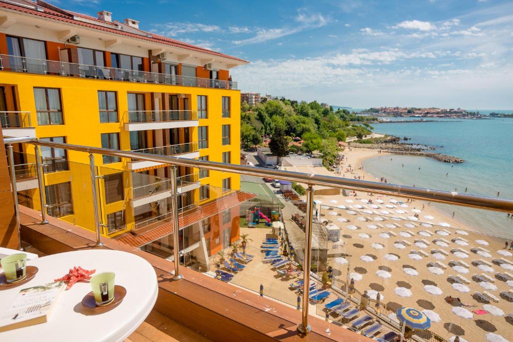 a balcony with a view of a beach and a yellow building at Apartment complex Mirage of Nessebar in Nesebar