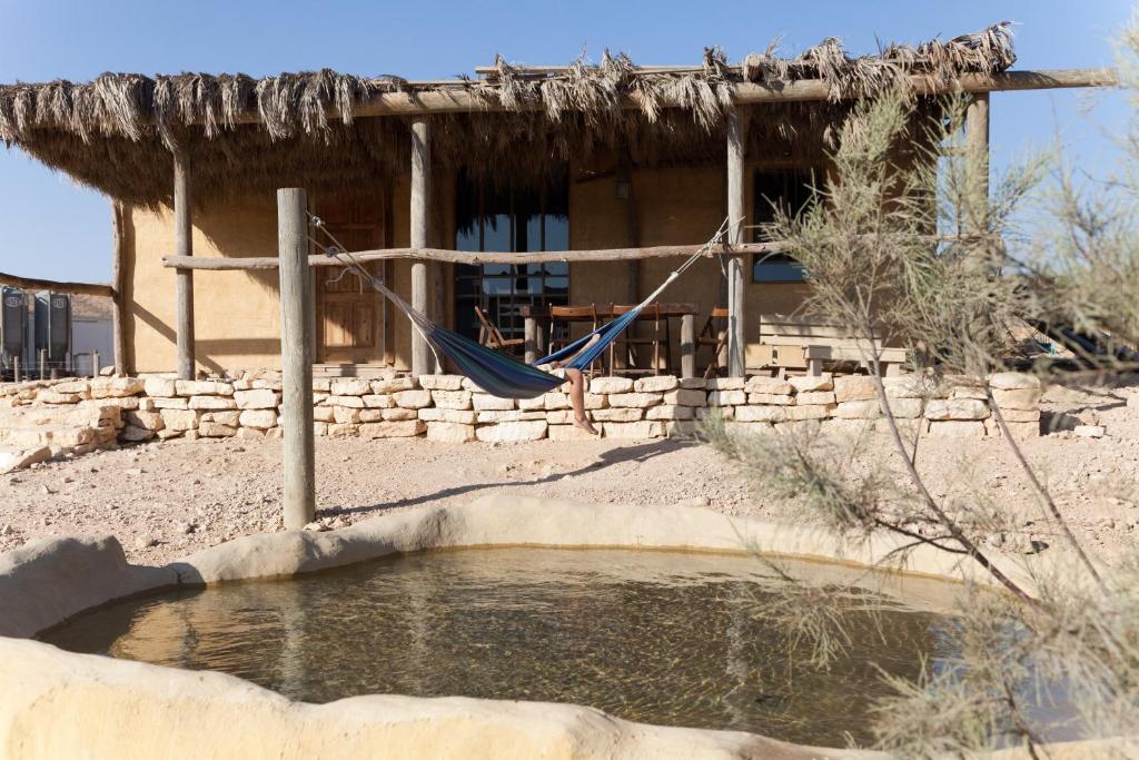 a house with a hammock and a pool of water at Naot Farm in Mashabbe Sade