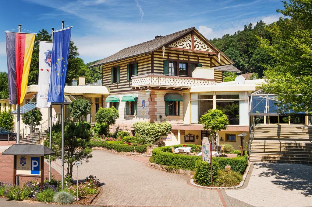 une grande maison avec drapeaux devant elle dans l'établissement Hotel Villa Marburg im Park, à Heigenbrücken