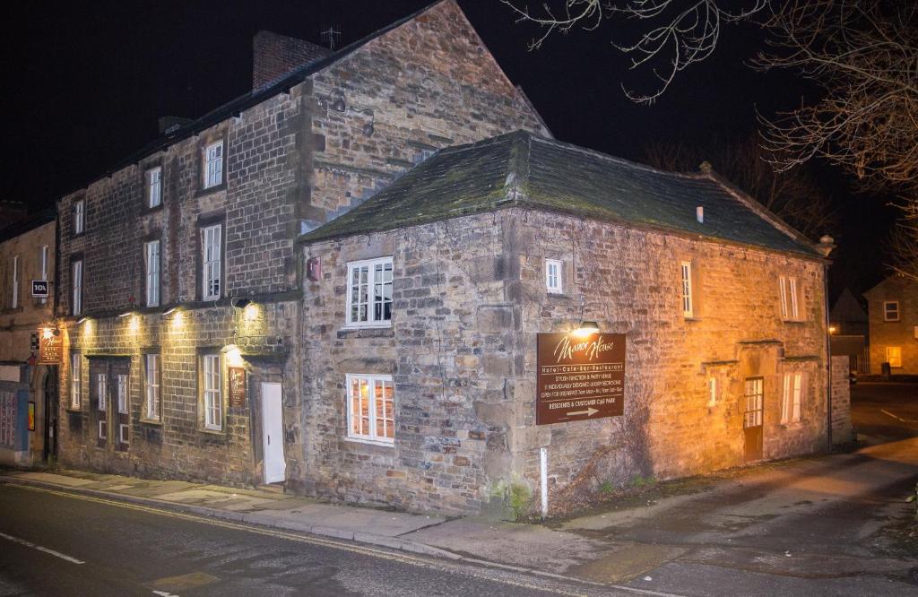 an old stone building on a street at night at The Manor House Hotel in Dronfield