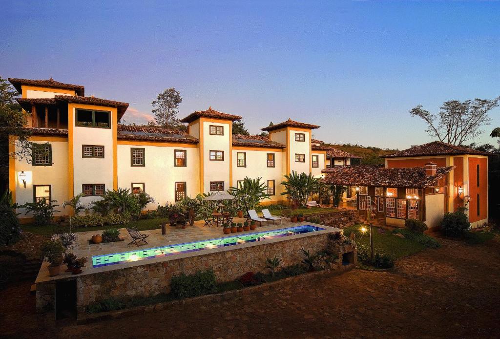 a large house with a swimming pool in front of it at Pousada d'Oleo de Guignard in Tiradentes