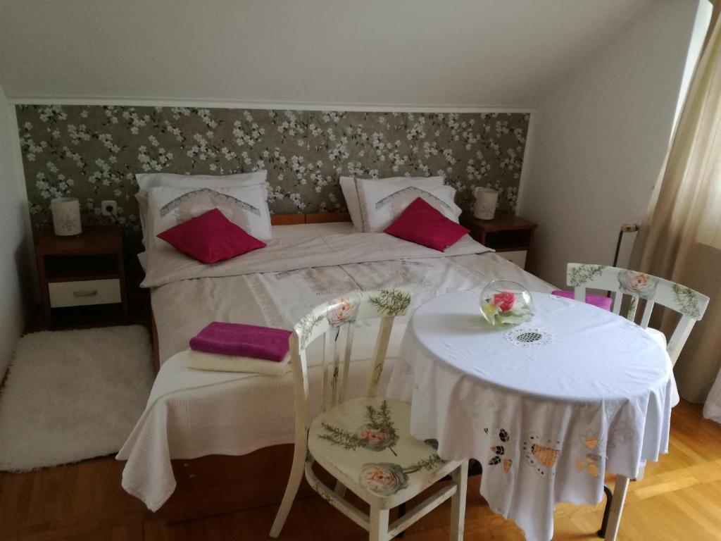 a bedroom with a bed with a table and chairs at Apartman Jasmin in Čatrnja