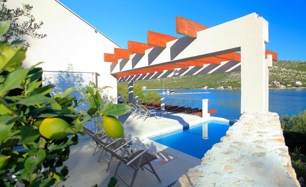 a swimming pool with a pergola next to the water at Villa Tapenade in Lastovo