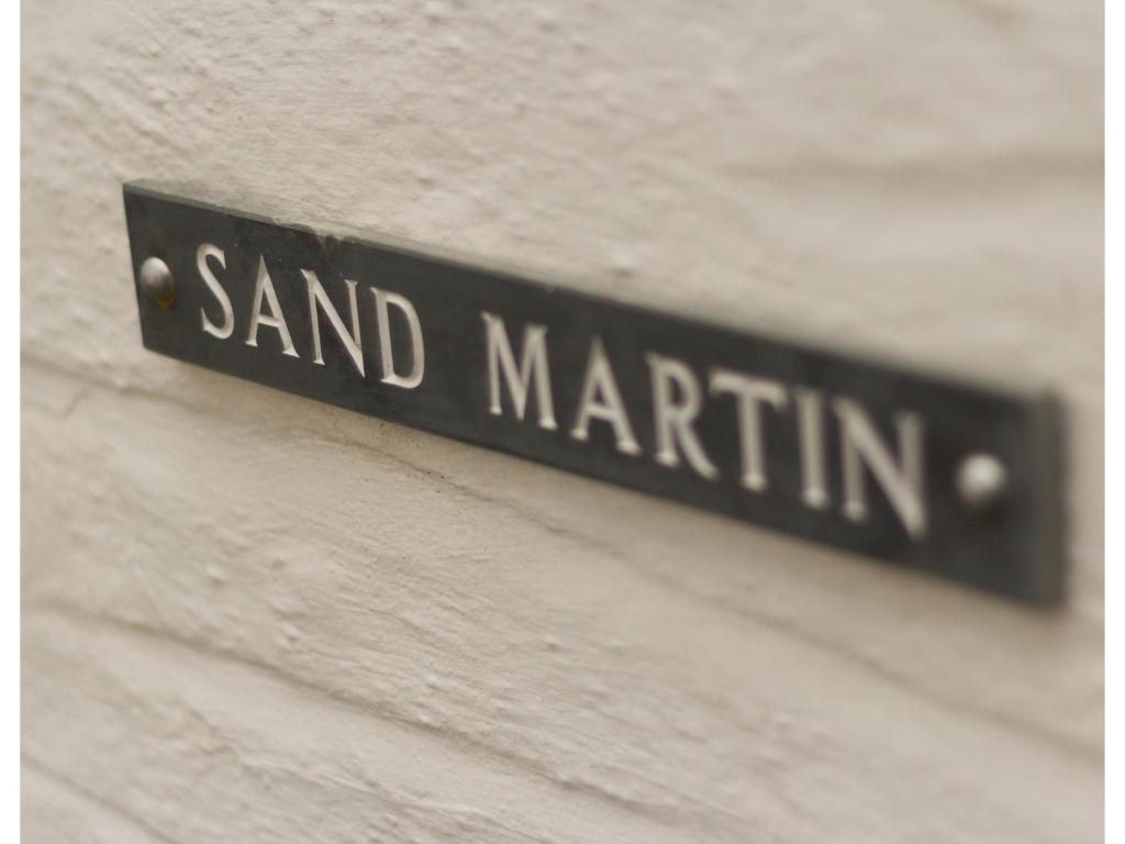 a sign that reads sand martin on a wall at Sand Martin in Looe