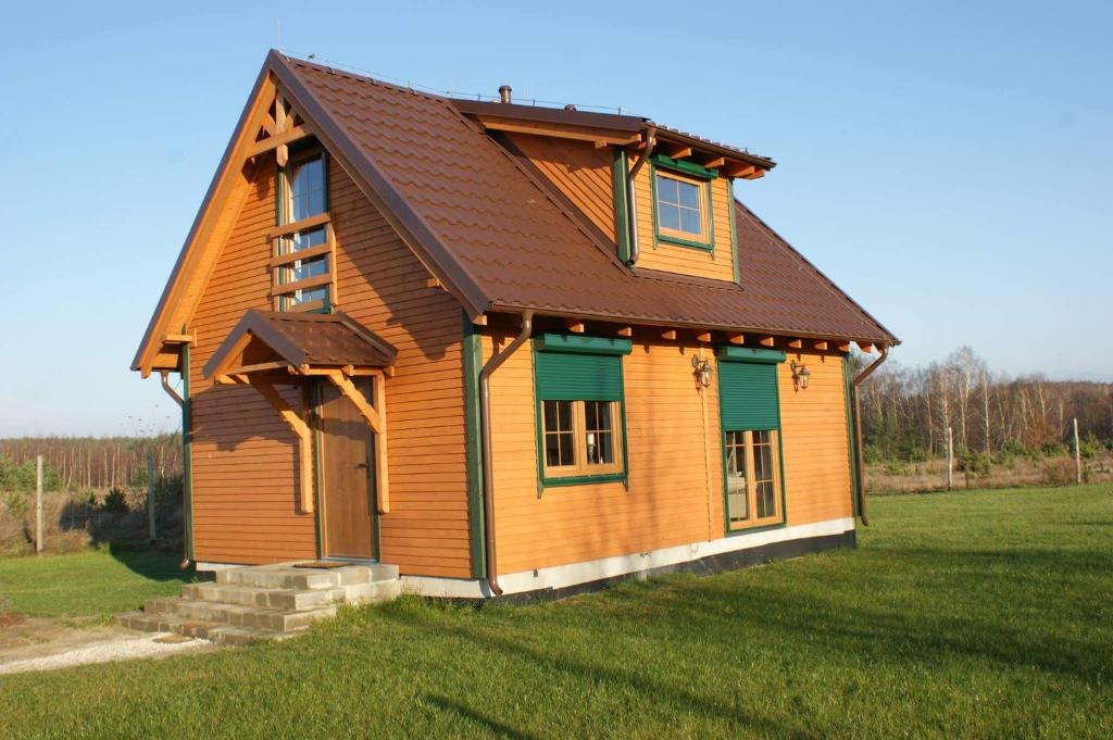 una pequeña casa de madera con techo marrón en Lavender Cottage en Charzykowy