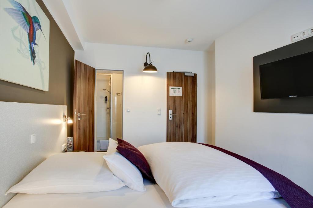 a bedroom with a white bed and a flat screen tv at Hotel West in Hamburg