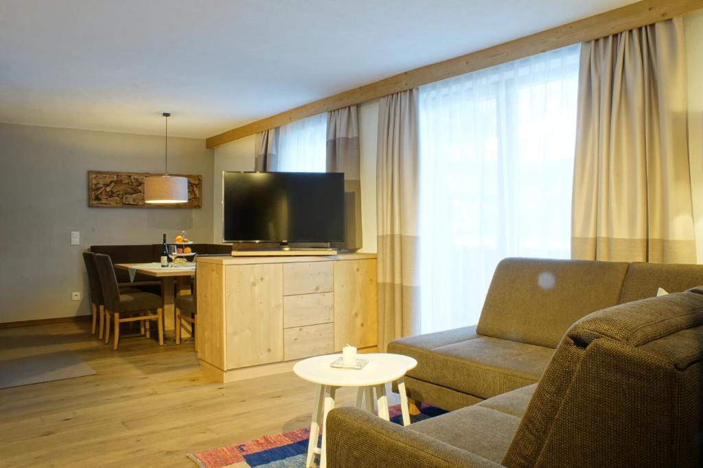 ein Wohnzimmer mit einem Sofa, einem TV und einem Tisch in der Unterkunft Gästehaus Prock in Mieders