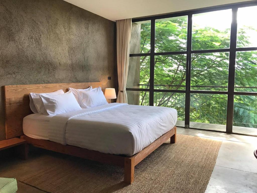 a bedroom with a bed and a large window at Inchantreedoopool in Kanchanaburi City