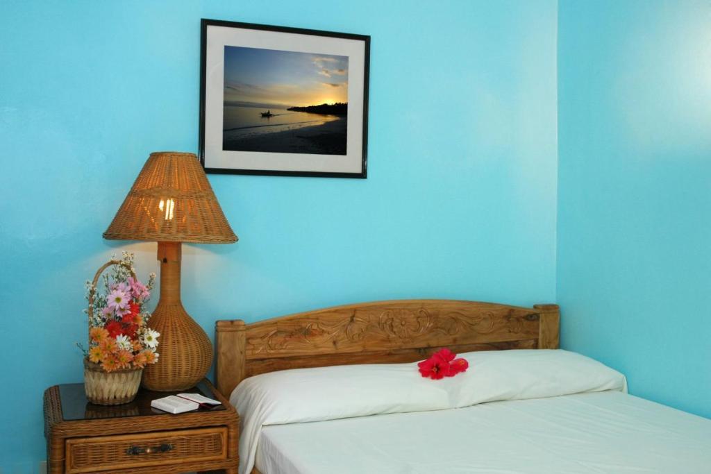 a bedroom with a blue wall with a bed and a lamp at Masamayor's Beach House and Resort in Camotes Islands