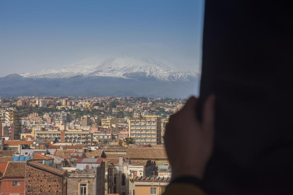 una persona che guarda fuori da una finestra su una montagna innevata di Turiddu B&B a Catania