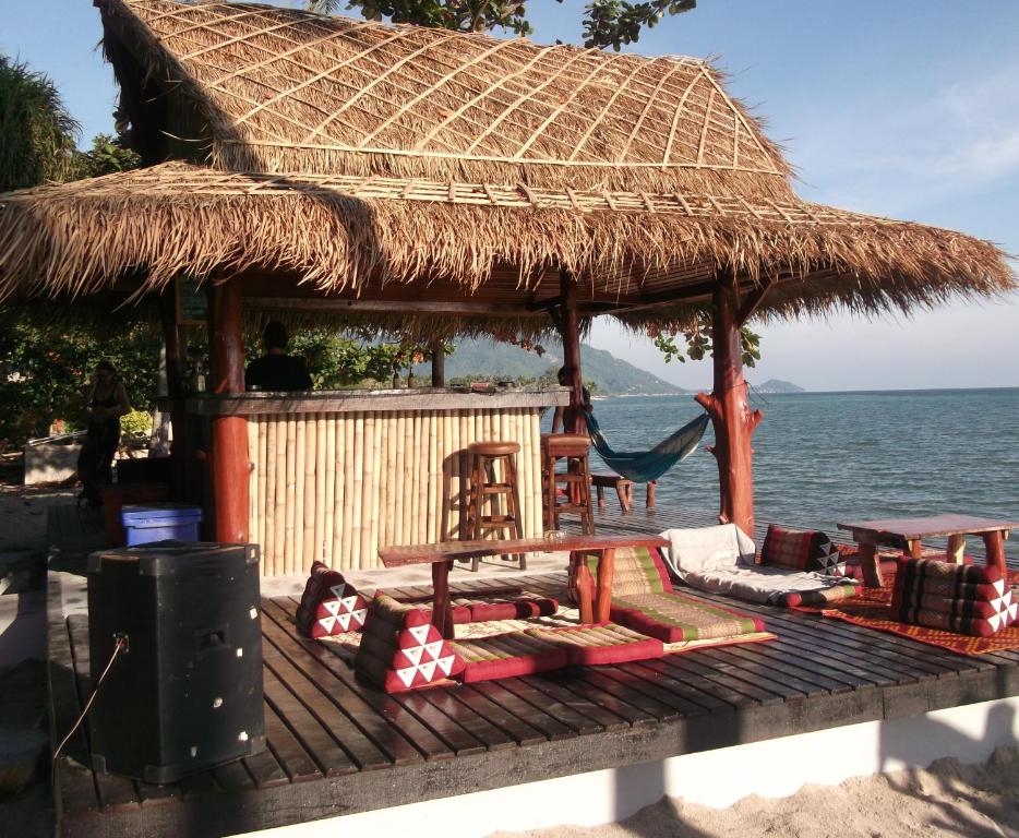 a hut on the beach with chairs and a table at Coco Garden Resort in Thongsala