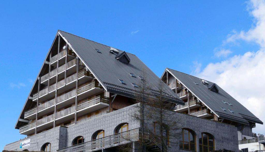 un bâtiment avec deux toits au-dessus dans l'établissement Résidence Goélia Les Chalets de Super-Besse, à Super-Besse