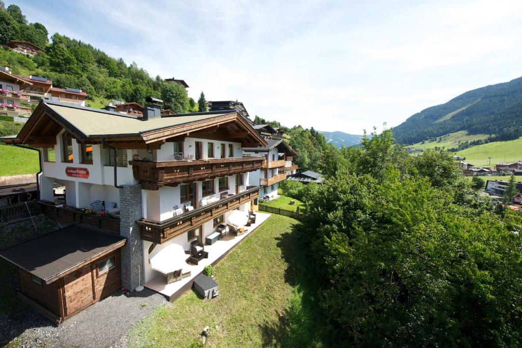 a house on a hill with mountains in the background at Landhaus Kendler in Saalbach Hinterglemm