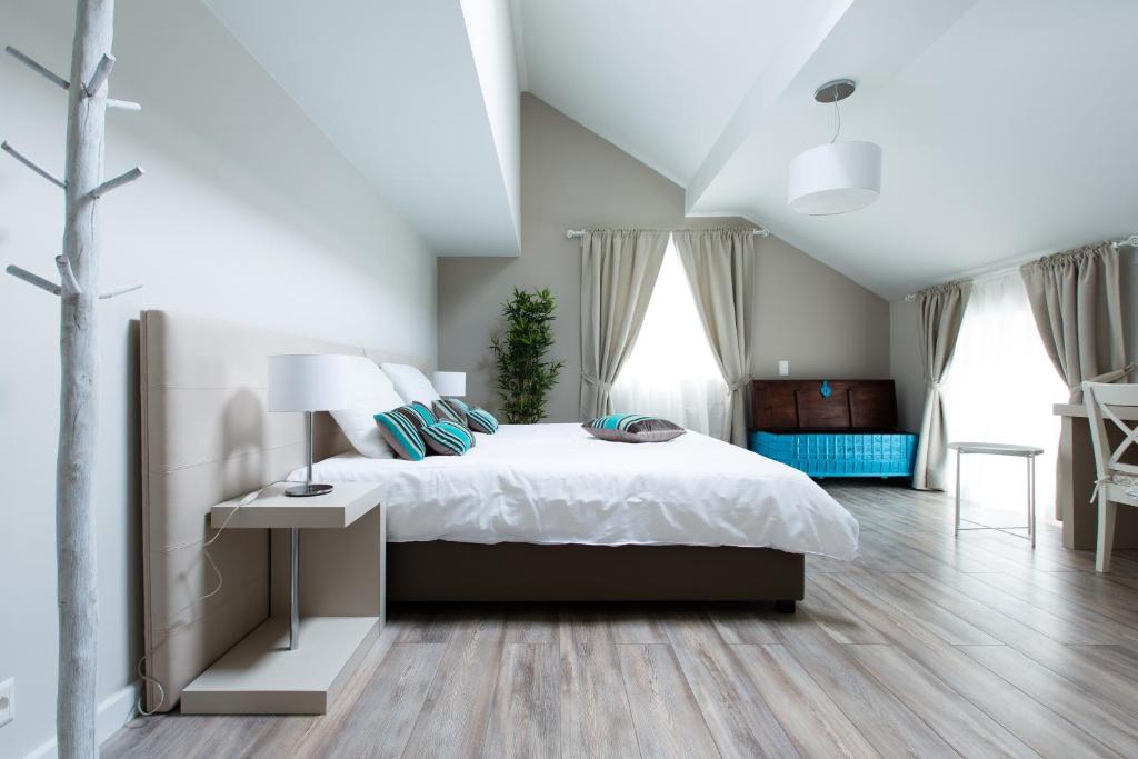 um quarto com uma grande cama branca e pisos em madeira em Auberge des Grands Bois em Buchillon
