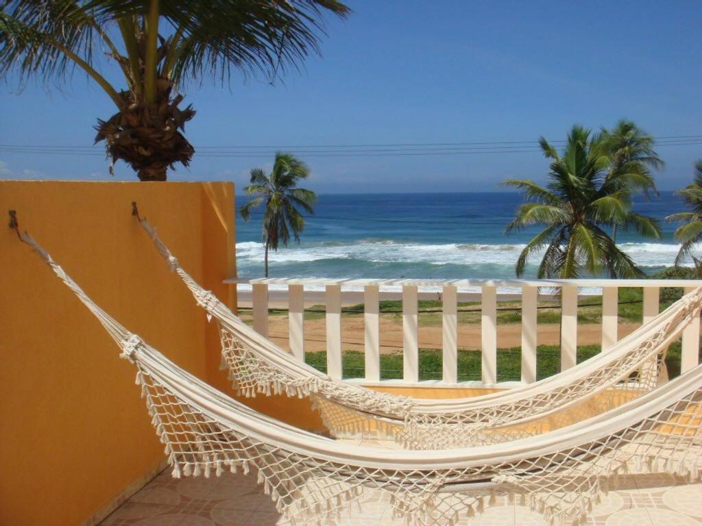 eine Hängematte auf dem Balkon mit Blick auf den Strand in der Unterkunft Duplex na beira da praia, de frente pro mar in Salvador