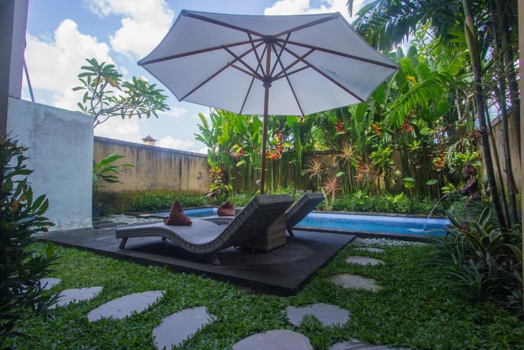 patio con sedia e ombrellone accanto alla piscina di Sebujan Grand Aurora ad Ubud