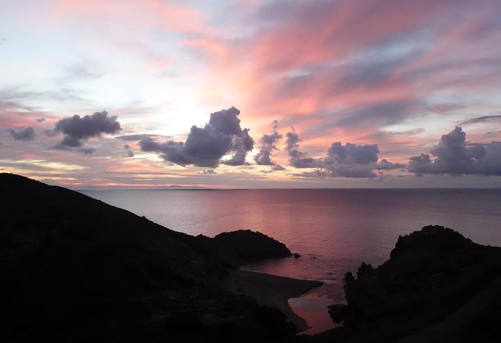 un coucher de soleil sur l'océan avec des rochers au premier plan dans l'établissement ARTEMIS STUDIO - NAS, à Armenistis