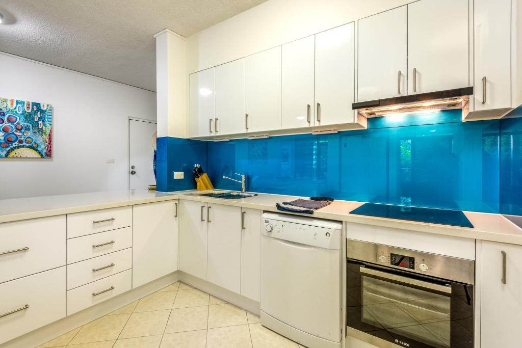 a kitchen with white cabinets and blue walls at Tranquility Chill at Palm Cove in Cairns