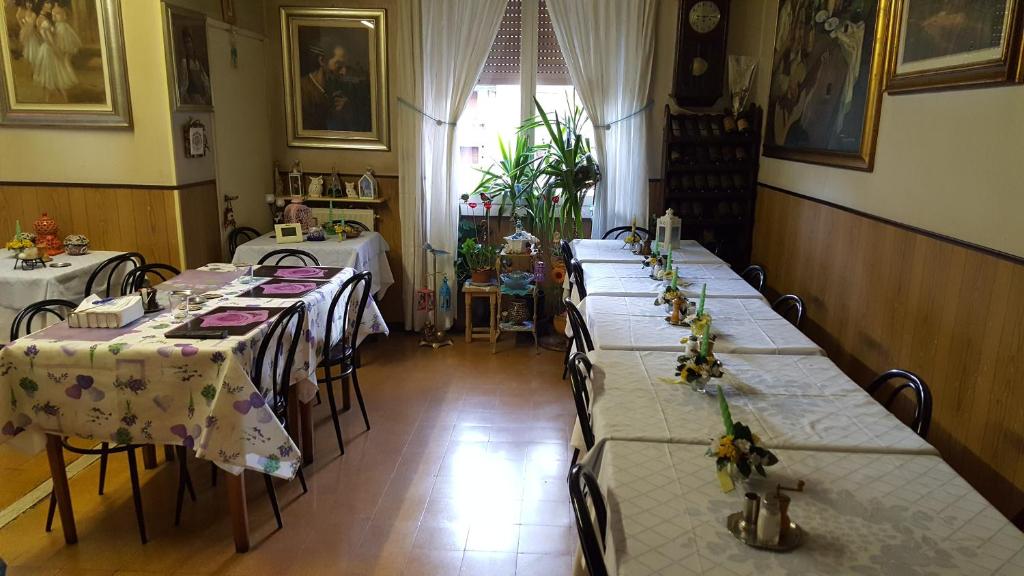 une salle avec quatre tables avec des nappes blanches dans l'établissement Pensione Santachiara, à Sanremo
