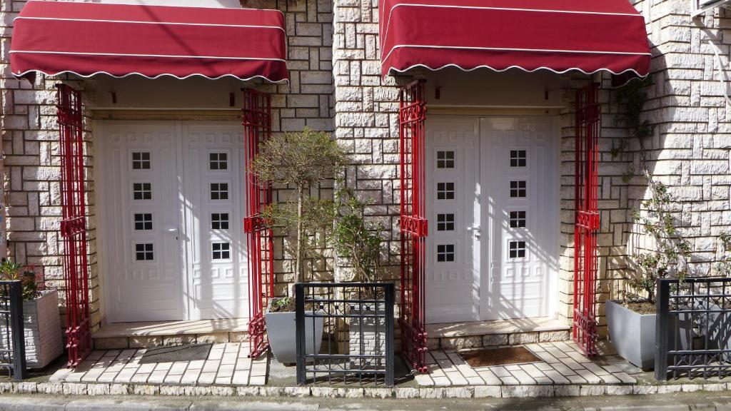 dwa białe drzwi na budynku z czerwonymi markizami w obiekcie Andi Apartments w Tiranie